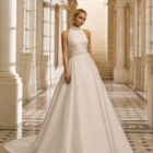Vestido de novia Aire Barcelona 2027 de mikado con escote halter, cintura marcada y falda línea A de estilo minimalista y elegante.