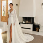 Vestido de novia Raya de Aire Barcelona 2027 de corte A en gasa plisada con escote en pico, cuerpo de encaje floral, espalda abierta y abertura frontal en la falda.