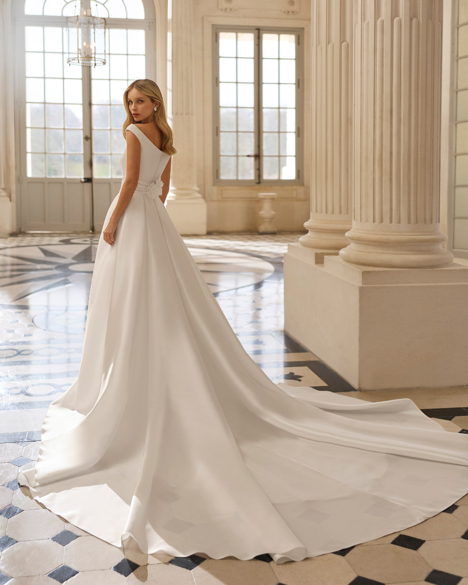 Vestido de novia Bacara de Aire Barcelona 2027 con escote barco, espalda en V, cintura de encaje y falda fluida de crepé.