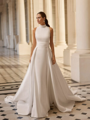 Vestido de novia Bahamas de Aire Barcelona 2027 con cuello halter, corte evasé, sobrefalda desmontable y espalda descubierta.