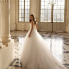 Vestido de novia Betia de Aire Barcelona 2027 de corte princesa con corpiño de encaje floral, escote cuadrado, falda de tul de gran volumen y gargantilla de encaje.