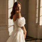 Vestido de novia Beyda de Aire Barcelona 2027 con escote barco, cuerpo corsé de encaje, mangas abullonadas desmontables y falda princesa con abertura.