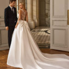Vestido de novia Blayra de Aire Barcelona 2027 confeccionado en mikado con escote barco, espalda transparente bordada y gran lazo en la cintura.