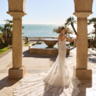 Vestido de novia Fado de Luna Novias 2027 de corte sirena en encaje, escote profundo en V, mangas japonesas de encaje y espalda abierta con delicados tirantes de pedrería.