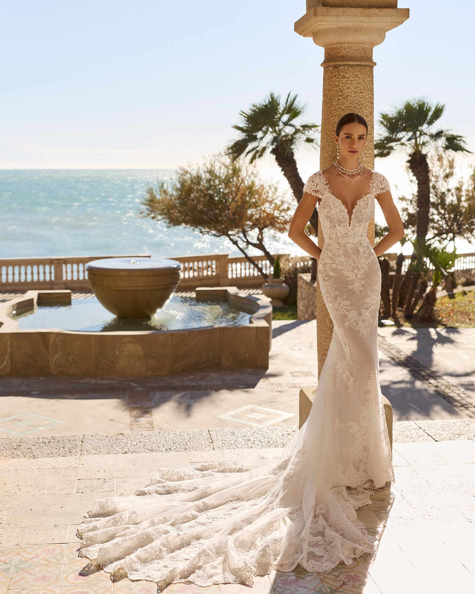 Vestido de novia Fado de Luna Novias 2027 de corte sirena en encaje, escote profundo en V, mangas japonesas de encaje y espalda abierta con delicados tirantes de pedrería.