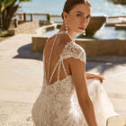 Vestido de novia Fado de Luna Novias 2027 de corte sirena en encaje, escote profundo en V, mangas japonesas de encaje y espalda abierta con delicados tirantes de pedrería.