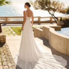 Vestido de novia Feliz de Luna Novias 2027 de corte A en gasa con cuerpo de encaje floral, espalda descubierta, delicados detalles de plumas en los hombros y falda fluida.
