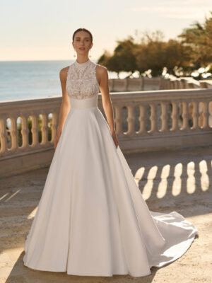 Vestido de novia Fluvia de Luna Novias 2027 de corte princesa, cuello alto y cuerpo de encaje bordado con falda lisa.