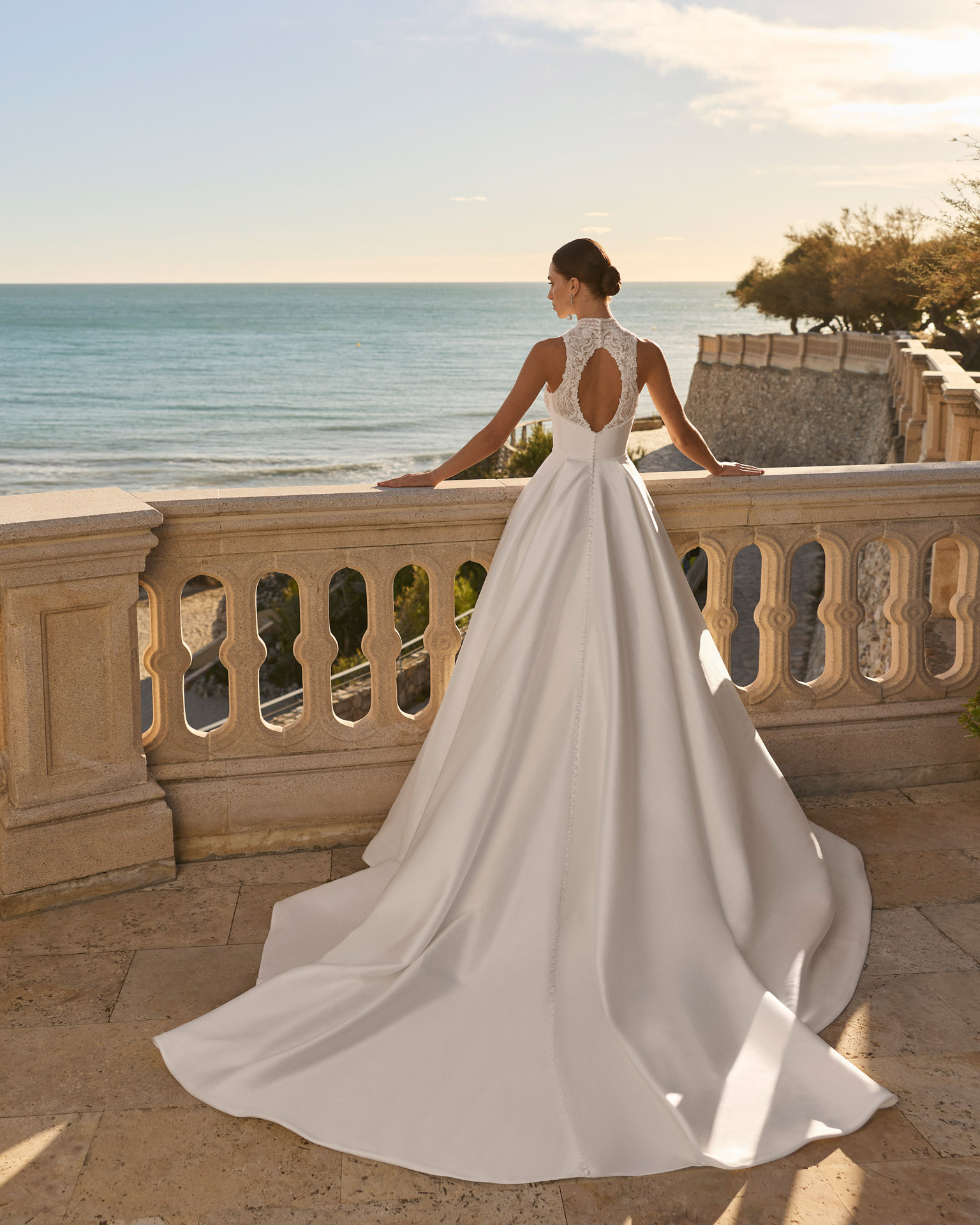 Vestido de novia Fluvia de Luna Novias 2027 de corte princesa, cuello alto y cuerpo de encaje bordado con falda lisa.
