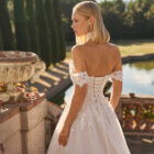 Vestido de novia Fresa de Luna Novias 2027 de corte A con escote barco, mangas caídas de encaje floral, delicado choker de encaje y falda de tul con aplicaciones florales.