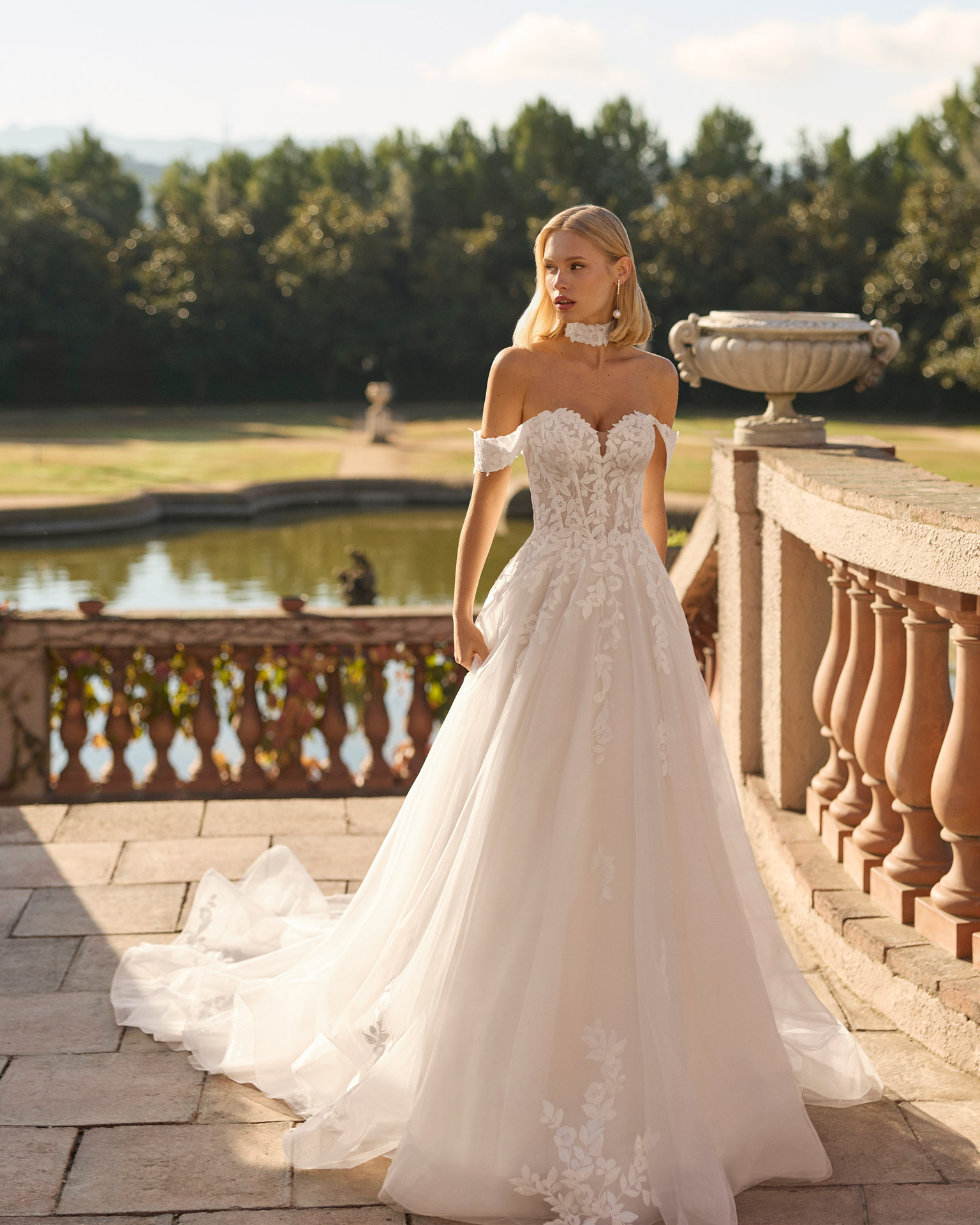 fresa-vestido-novia-corte-a-encaje-floral-escote-barco-luna-novias-2027.frente Vestido de novia Fresa de Luna Novias 2027 de corte A con escote barco, mangas caídas de encaje floral, delicado choker de encaje y falda de tul con aplicaciones florales.