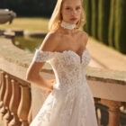 Vestido de novia Fresa de Luna Novias 2027 de corte A con escote barco, mangas caídas de encaje floral, delicado choker de encaje y falda de tul con aplicaciones florales.