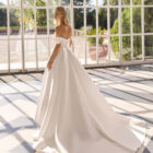 Vestido de novia Fulvia de Luna Novias 2027 de corte princesa, escote barco con hombros descubiertos, cuerpo corsé y falda amplia con cola.