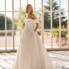 Vestido de novia Fulvia de Luna Novias 2027 de corte princesa, escote barco con hombros descubiertos, cuerpo corsé y falda amplia con cola.