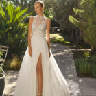 Vestido de novia Malu de Alma Novia 2027 de línea A con cuello halter de encaje, cuerpo bordado, falda de tul con abertura y espalda descubierta.