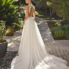 Vestido de novia Malu de Alma Novia 2027 de línea A con cuello halter de encaje, cuerpo bordado, falda de tul con abertura y espalda descubierta.