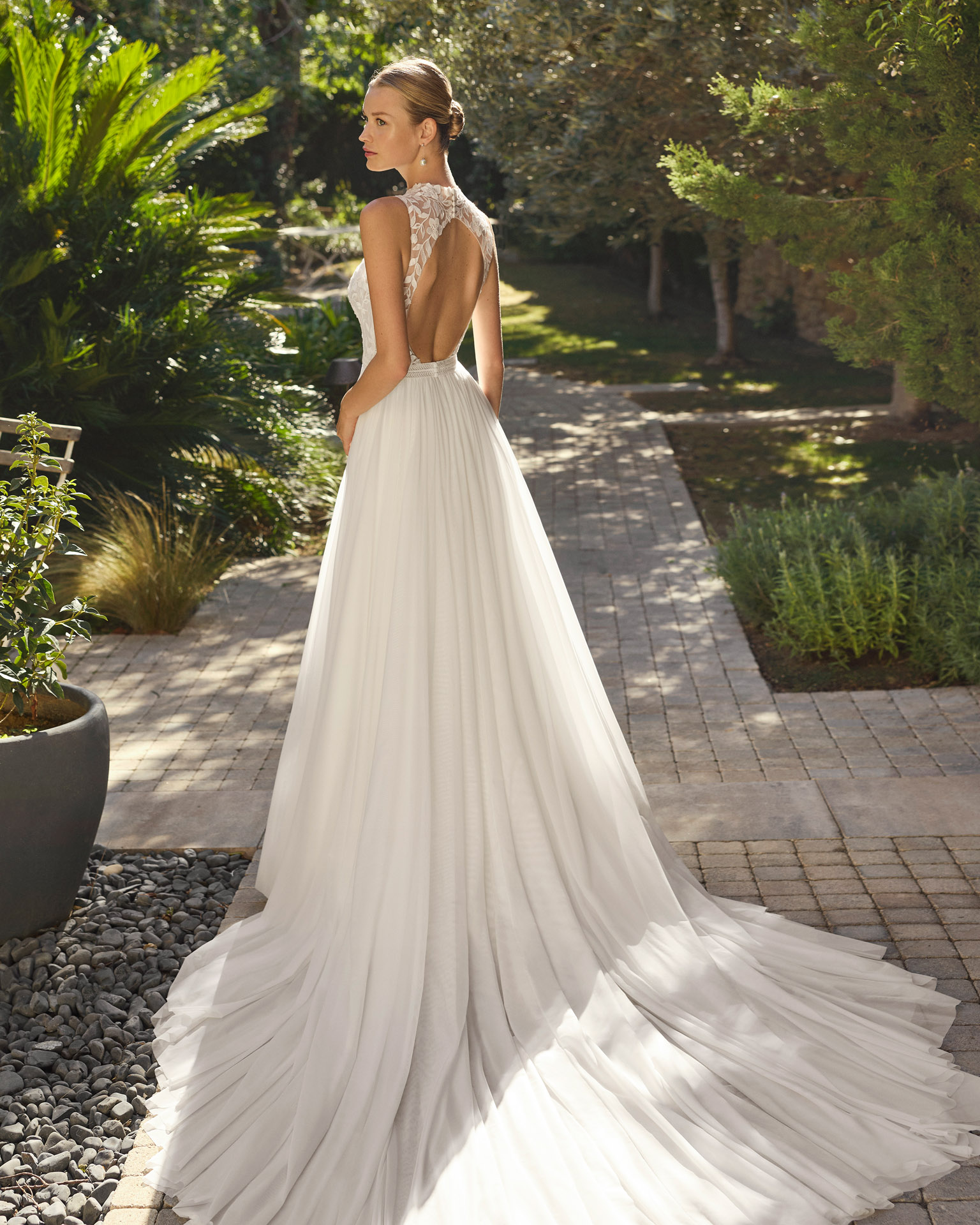 Vestido de novia Malu de Alma Novia 2027 de línea A con cuello halter de encaje, cuerpo bordado, falda de tul con abertura y espalda descubierta.