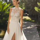 Vestido de novia Malu de Alma Novia 2027 de línea A con cuello halter de encaje, cuerpo bordado, falda de tul con abertura y espalda descubierta.