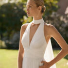 Vestido de novia Malvin de Alma Novia 2027 de corte A en tul plisado, escote halter con cuello envolvente, abertura en la falda y espalda descubierta.