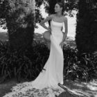 Vestido de novia Marga de Alma Novia 2027 de corte sirena en crepé, escote recto con finos tirantes y espectacular cola de encaje floral.