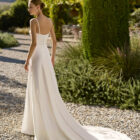 Vestido de novia Marny de Alma Novia 2027 confeccionado en crepé con escote cuadrado, tirantes finos y elegante capa de gasa de estilo minimalista.