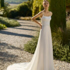 Vestido de novia Marny de Alma Novia 2027 confeccionado en crepé con escote cuadrado, tirantes finos y elegante capa de gasa de estilo minimalista.