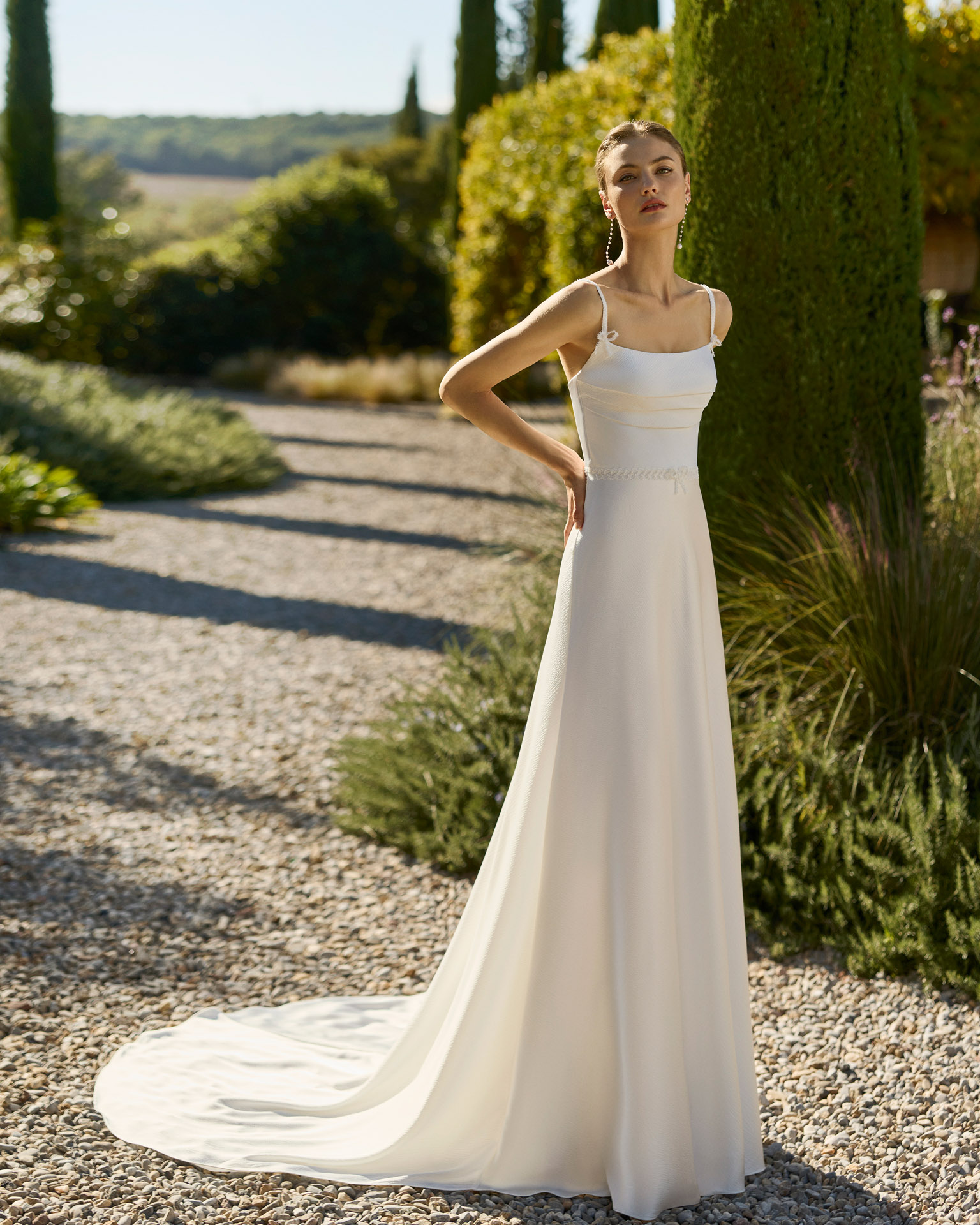 Vestido de novia Marny de Alma Novia 2027 confeccionado en crepé con escote cuadrado, tirantes finos y elegante capa de gasa de estilo minimalista.