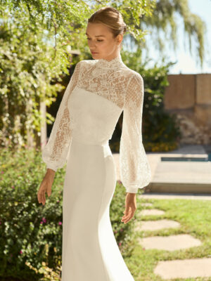 Vestido de novia Megan de Alma Novia 2027 con escote palabra de honor, silueta sirena y chaqueta de encaje desmontable de cuello alto y manga larga.