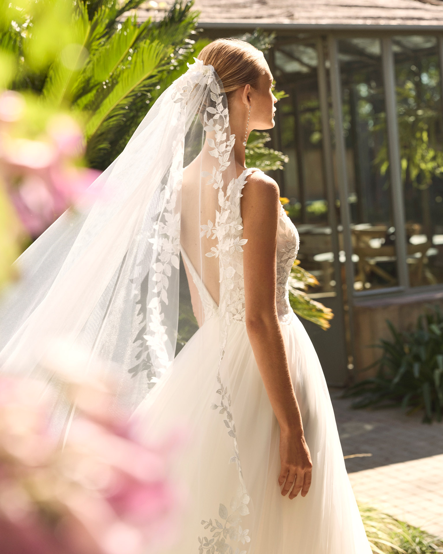 Vestido de novia Milano de Alma Novia 2027 con escote pico, cuerpo de encaje floral, falda de tul con abertura delantera y silueta romántica.