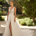 Vestido de novia Milano de Alma Novia 2027 con escote pico, cuerpo de encaje floral, falda de tul con abertura delantera y silueta romántica.
