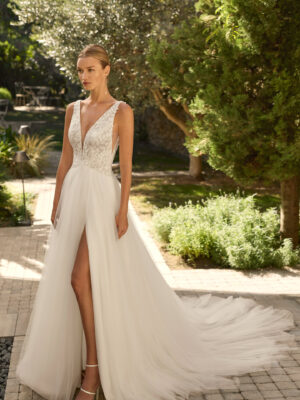 Vestido de novia Milano de Alma Novia 2027 con escote pico, cuerpo de encaje floral, falda de tul con abertura delantera y silueta romántica.