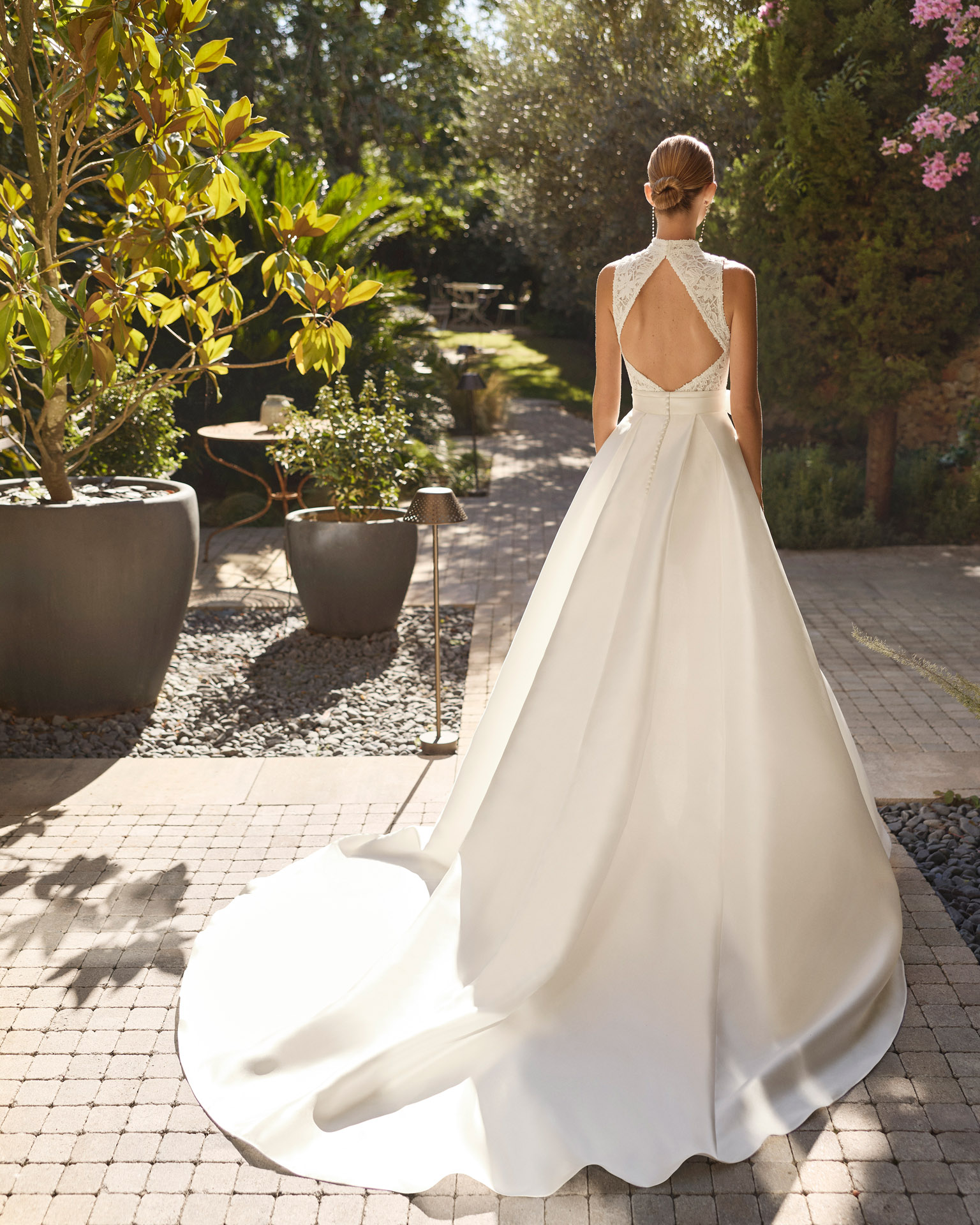 Vestido de novia Mirena de Alma Novia 2027 con vestido corto de encaje floral de cuello alto y elegante sobrefalda desmontable con gran lazada.