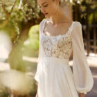 Vestido de novia Moira de Alma Novia 2027 con escote cuadrado, cuerpo de encaje floral, falda de crepé con abertura delantera y estilo romántico.