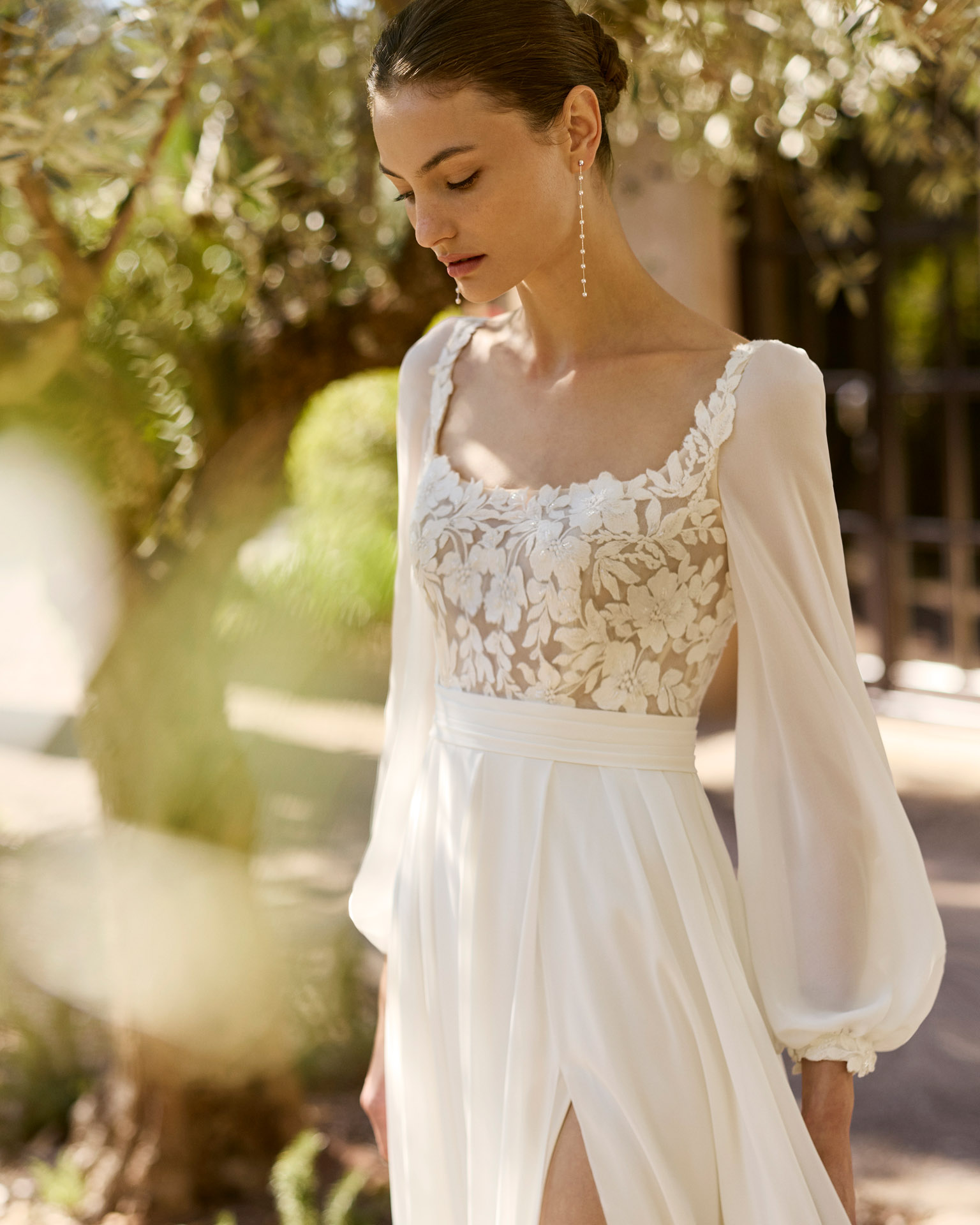 Vestido de novia Moira de Alma Novia 2027 con escote cuadrado, cuerpo de encaje floral, falda de crepé con abertura delantera y estilo romántico.