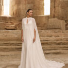 Vestido de novia Palermo de Adriana Alier 2027 con escote en pico, espalda drapeada, tirantes joya y falda fluida de crepé.