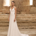 Vestido de novia Palermo de Adriana Alier 2027 con escote en pico, espalda drapeada, tirantes joya y falda fluida de crepé.