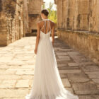 Vestido de novia Palmer de Adriana Alier 2027 con escote halter, falda de gasa plisada, espalda abierta con tirantes joya y estilo romántico.