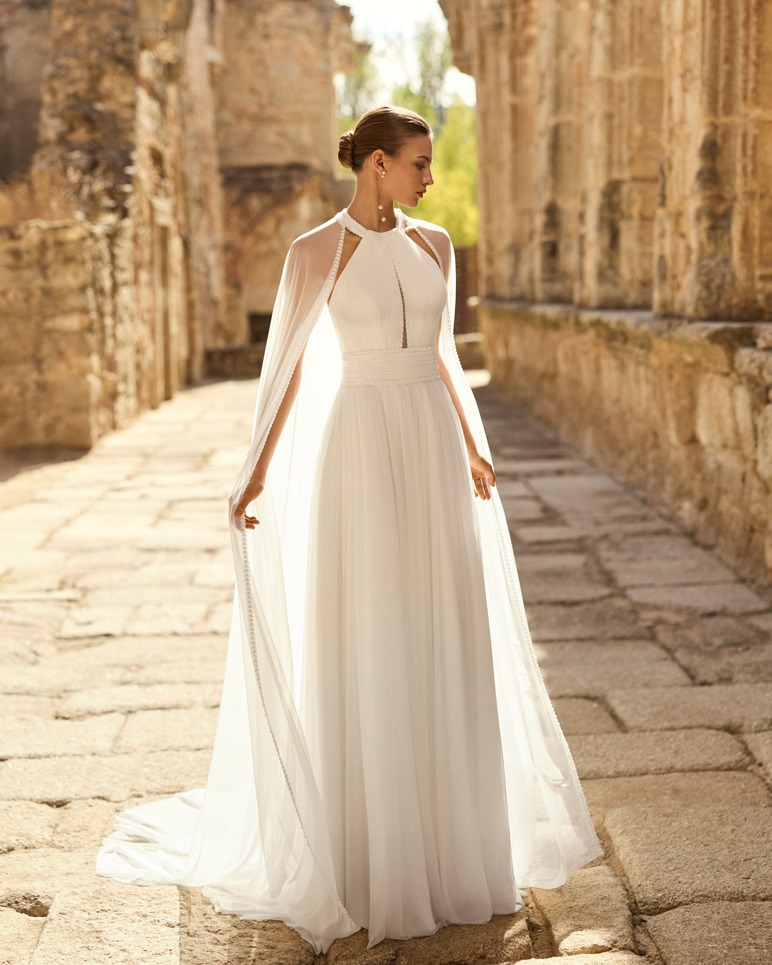 palmer-vestido-novia-gasa-escote-halter-espalda-abierta-adriana-alier-2027.FRENTE Vestido de novia Palmer de Adriana Alier 2027 con escote halter, falda de gasa plisada, espalda abierta con tirantes joya y estilo romántico.