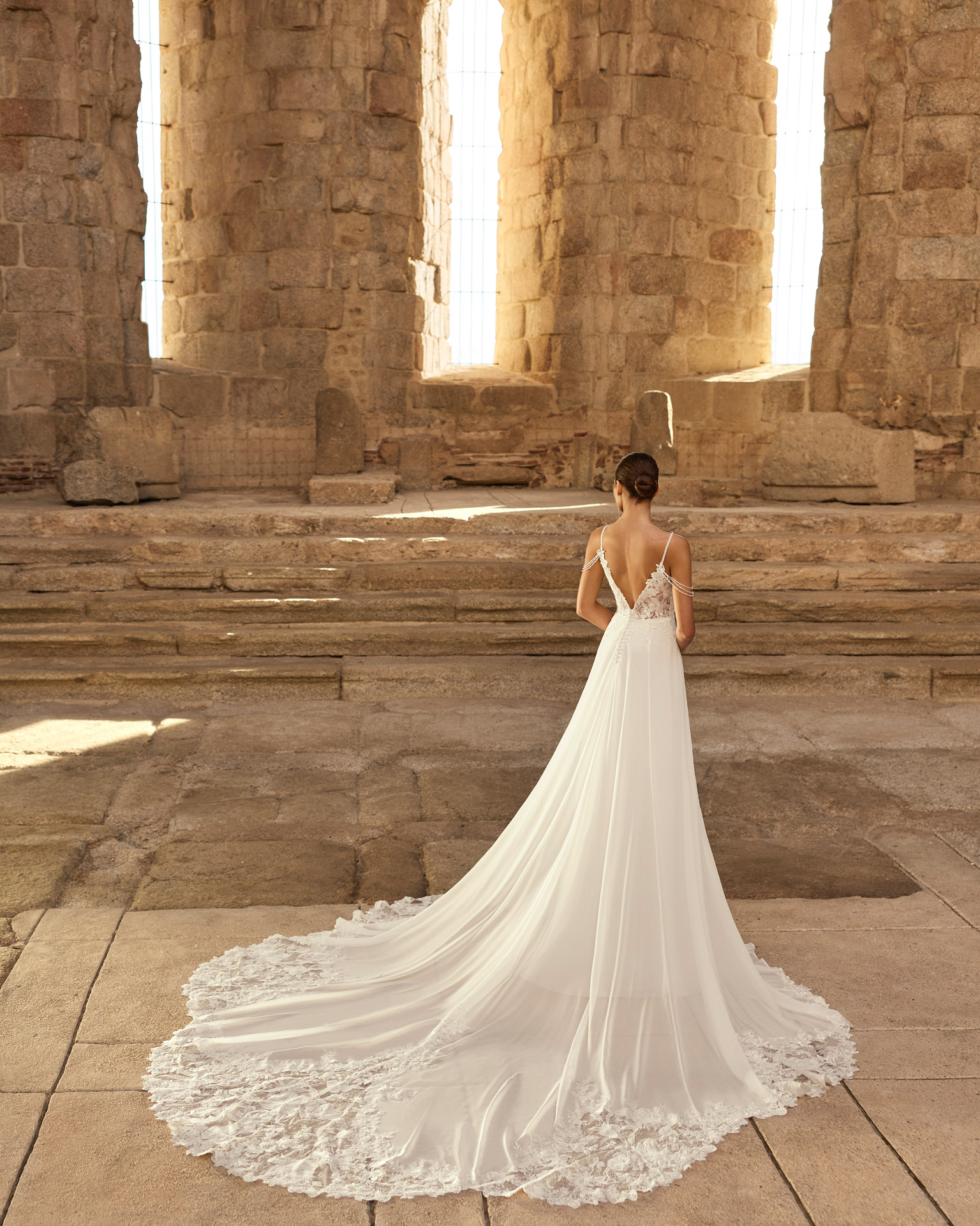 Vestido de novia Paraíso de Adriana Alier 2027 con cuerpo de encaje floral, escote en V, espalda descubierta, falda vaporosa y cola con aplicaciones de encaje.