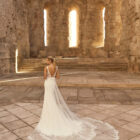 Vestido de novia Parvati de Adriana Alier 2027 de corte sirena en crepé con aplicaciones de encaje floral, escote barco, espalda escotada en V y cola de tul bordada.