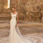 Vestido de novia Parvati de Adriana Alier 2027 de corte sirena en crepé con aplicaciones de encaje floral, escote barco, espalda escotada en V y cola de tul bordada.