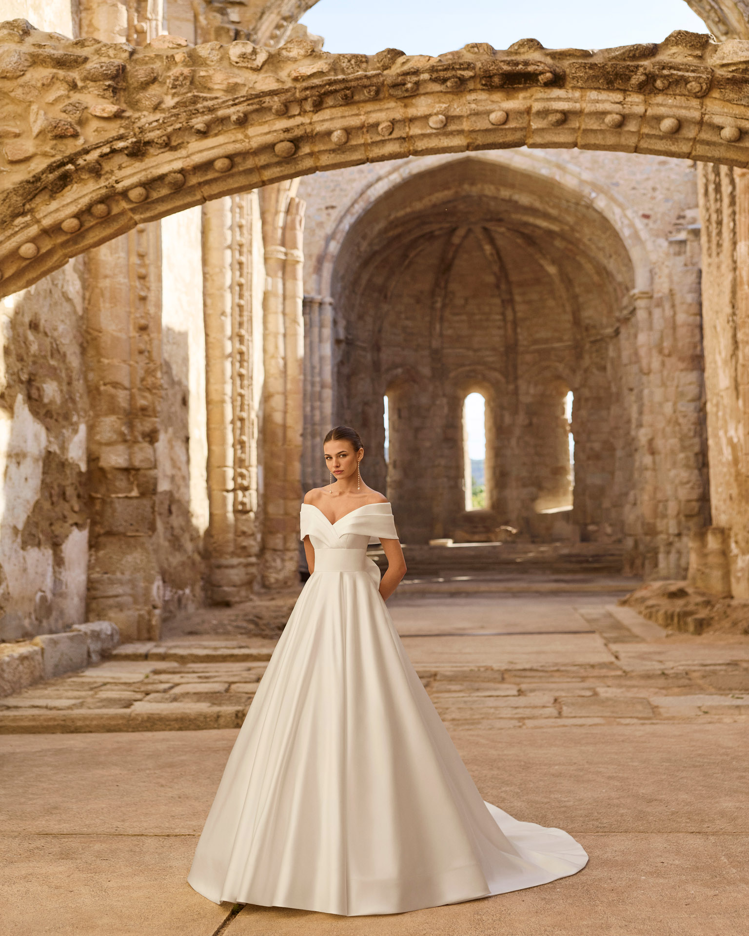 piuma-vestido-novia-princesa-escote-barco-adriana-alier-2027.frente Vestido de novia Piuma de Adriana Alier 2027 con escote barco caído, cuerpo estructurado, gran lazada en la espalda y falda princesa de mikado.