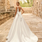 Vestido de novia Porto de Adriana Alier 2027 de línea A con escote cuadrado, abertura frontal, cintura de encaje y sobrefalda desmontable.