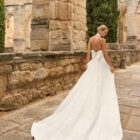 Vestido de novia Prado de Adriana Alier 2027 con cuello halter, espalda completamente descubierta, gran lazo posterior, falda de corte A con abertura lateral y tejido jacquard floral.