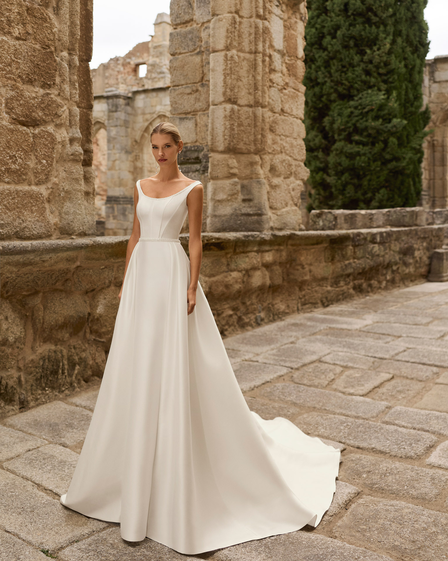 prina-vestido-novia-minimalista-linea-a-adriana-alier-2027.2 Vestido de novia Prina de Adriana Alier 2027 de línea A con escote barco, cuerpo liso, cintura marcada y falda de gran caída.