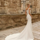 Vestido de novia Prina de Adriana Alier 2027 de línea A con escote barco, cuerpo liso, cintura marcada y falda de gran caída.
