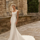 Vestido de novia Prina de Adriana Alier 2027 de línea A con escote barco, cuerpo liso, cintura marcada y falda de gran caída.