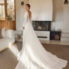 Vestido de novia Reina de Aire Barcelona 2027 con cuerpo de encaje, mangas largas de gasa, espalda ilusión y falda fluida de crepé.