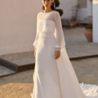 Vestido de novia Relia de Aire Barcelona 2027 con mangas largas de gasa transparente, escote barco, cintura de encaje, falda fluida de crepé y elegante espalda cerrada.