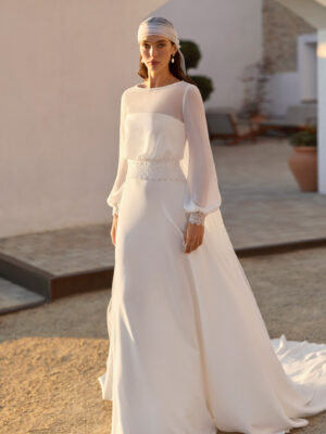 Vestido de novia Relia de Aire Barcelona 2027 con mangas largas de gasa transparente, escote barco, cintura de encaje, falda fluida de crepé y elegante espalda cerrada.